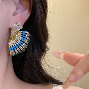 Close-up view of vintage fan-shaped stud earrings with colorful crystals on a model.
