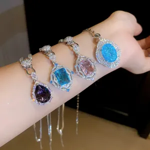 Detail view of vintage zircon pendants in teardrop, oval, and rectangular shapes on arm.