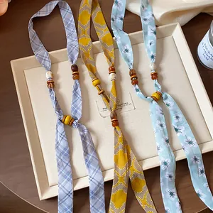 Detailed macro view of chiffon floral neck scarves with wooden beads in three colors.