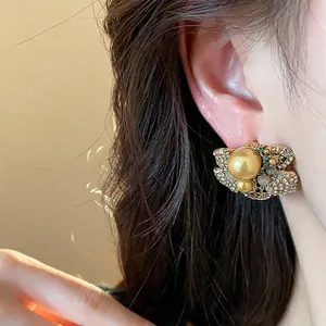 Vintage floral gold stud earrings featuring a large pearl and sparkling rhinestones