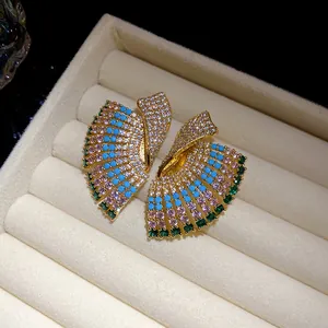 Macro shot of luxury vintage gold fan earrings with colorful crystals on velvet tray