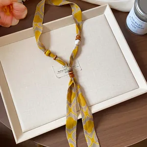 Close-up detail showing a chiffon printed scarf necklace with decorative wooden beads.