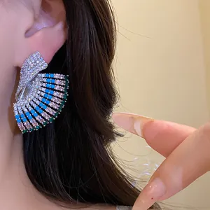 Close-up of vintage palace-style fan earrings with blue and green gemstones on silver needles.