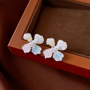 Vista detallada de pendientes elegantes con forma de flor, pétalos de colores y perlas