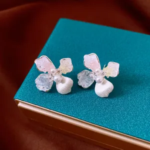 Vista detallada de pendientes de flores y perlas con pétalos de varios colores