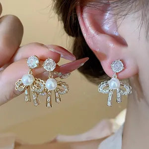 Detail view of elegant 18k gold plated bow earrings with pearls and sparkling zircons