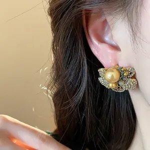 Close-up of vintage flower pearl stud earring with sparkling rhinestone accents on a model's ear.