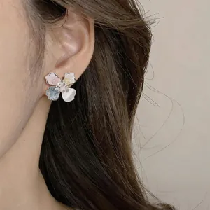 Primer plano detallado de elegantes pendientes de botón con flores y perlas en oreja