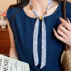 Close-up of a blue plaid chiffon necklace with wooden beads on denim clothing
