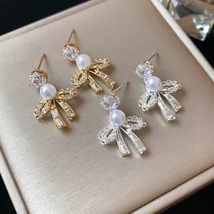 Macro view showing the intricate detail of pearl and zircon bow earrings on a beige box
