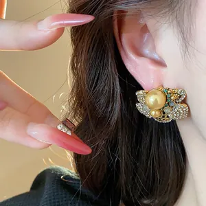 Detailed macro view of vintage flower pearl stud earrings with sparkling rhinestones on ear.