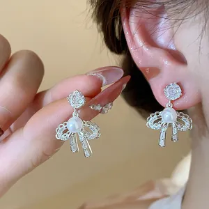 Detailed view of silver bow earrings with elegant pearls and sparkling zircons