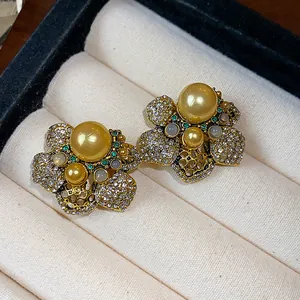 Detail view of vintage gold flower stud earrings featuring yellow pearls and rhinestones.