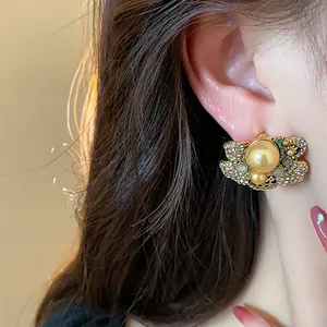 Close-up of vintage gold-toned flower stud earring with pearls and rhinestones on ear