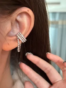 Dettaglio di un ear cuff asimmetrico con zirconi e perle indossato sull'orecchio