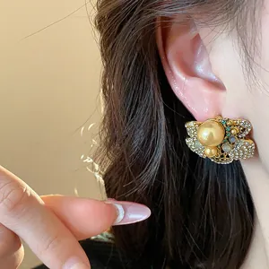 Close-up detail of vintage gold pearl earring with rhinestones on model's ear