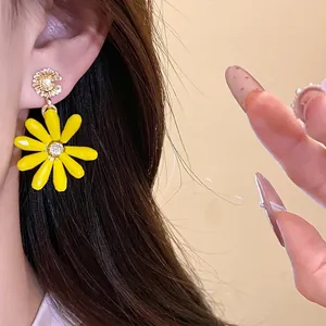 Handmade yellow glass flower drop earrings with silver needle shown on model ear