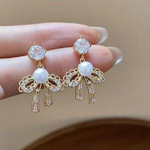 Elegant 18k gold-plated bow earrings featuring shimmering zircons and pearls detail