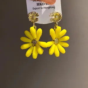 Close-up view of vibrant yellow daisy dangle earrings featuring intricate gold flower studs.