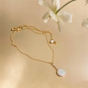 Detailed view of 18k gold-plated necklace with zircon-framed shell pendant and pearl.