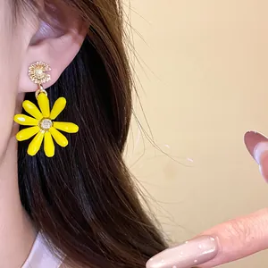 Close-up of vibrant yellow daisy flower pendant earrings worn on ear detail view
