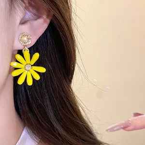 Close-up of vibrant yellow daisy flower drop earrings worn by an Asian fashion model.