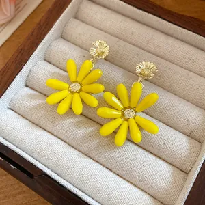 Detail view of yellow glass flower earrings with gold-toned center in a jewelry box