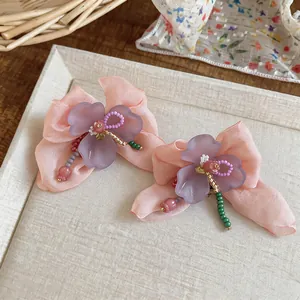 Close-up of sweet chiffon flower earrings with colorful glass beads on a tray.