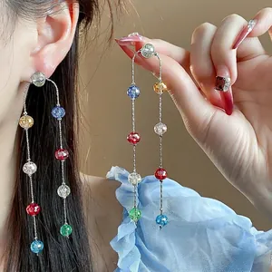 Colorful multifaceted glass beaded long tassel earrings worn by an elegant model