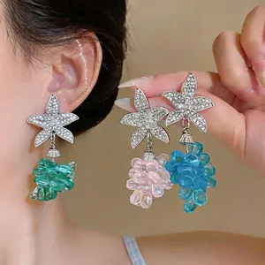 Vista macro de pendientes colgantes de estrella de mar y uva con pedrería brillante