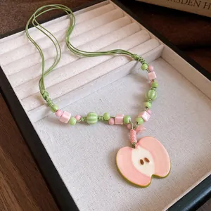Detailed view of handmade ceramic beaded necklace with fresh pink apple pendant