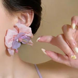 Close-up detail of chiffon flower earrings with purple glass beads on silver needle