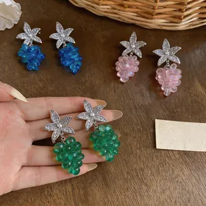 Primer plano de pendientes colgantes de racimo de uva de estrella de mar en mano.