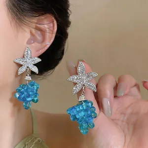 Detalle de pendientes de estrella de mar plateados con colgantes de uvas de perlas