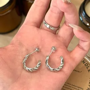 Close-up of twisted silver hoop earrings with micro-pave zircons for a stylish look