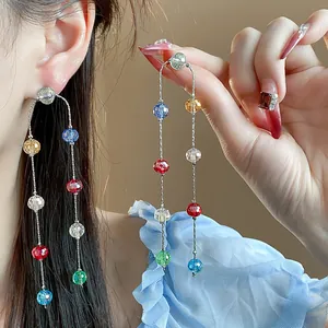 Detail of multi-colored faceted glass bead long tassel earrings shown on a model's ear