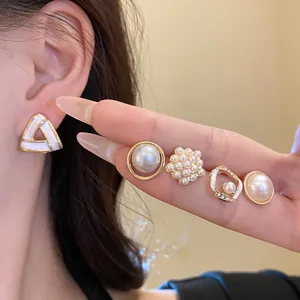 Primo piano di set orecchini geometrici con perle e aghi d'argento sulla mano di una modella
