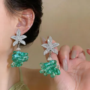 Detalle de pendientes de estrella de mar con cristales y colgantes de cuentas verdes tipo uva.
