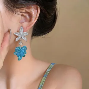 Primer plano de elegantes pendientes de estrella de mar con colgante de uva azul
