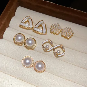 Dettaglio di un set di 5 paia di orecchini di perle con design geometrici e fiori.