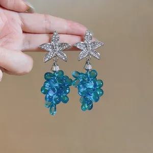Detalle de pendientes de estrella de mar plateada con colgantes de racimo de uvas azul translúcido