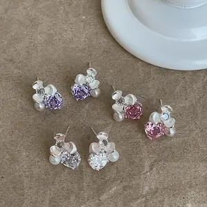 Detail view of colorful floral stud earrings with sparkling zircons and pearls.