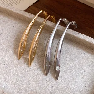 Detailed view of minimalist gold and silver teardrop earrings on stone tray