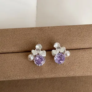 Detailed view of floral stud earrings with purple zircon and soft pink pearl accents.