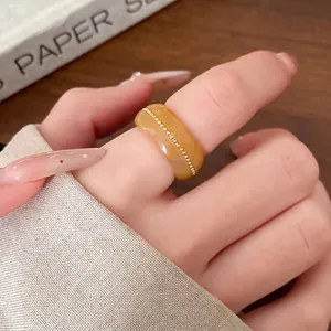 Elegant yellow marbled resin ring with gold bead inlay detail for a minimalist fashion look