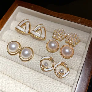 Elegante varietà di orecchini a perno con perle geometriche in un portagioie di velluto.