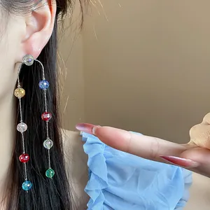 Close-up of colorful glass bead tassel earrings on model with light blue ruffles.