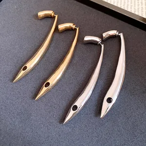 Close-up macro view of minimalist curved metal drop earrings in gold and silver finishes