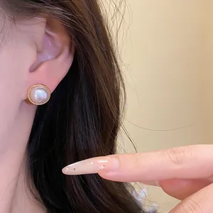 Dettaglio di un elegante orecchino a bottone con perla in stile francese e bordo dorato