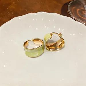 Dettaglio di orecchini a cerchio placcati oro 18 carati con smalto marmorizzato verde